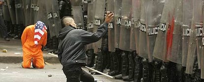 En la imagen, un joven junto a un hombre vestido como un preso de Guantánamo, se enfrenta a los antidisturbios en Bogotá.