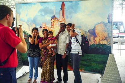El souvenir: una familia india se fotografía ante una imagen del despegue de un transbordador espacial.