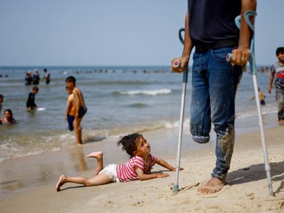 Una niña palestina tumbada en la playa de Rafah junto a un hombre tullido este miércoles en el sur de la franja de Gaza.