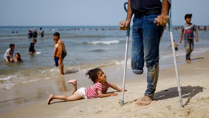 Una niña palestina tumbada en la playa de Rafah junto a un hombre tullido este miércoles en el sur de la franja de Gaza.