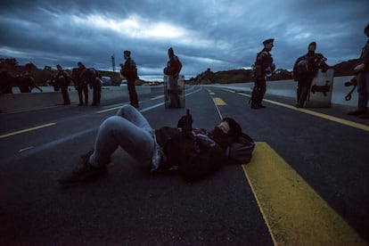 Un manifestant estirat consultant el mòbil davant dels gendarmes francesos en el tram de l'autopista AP-7.