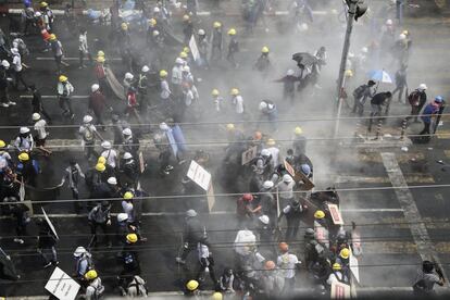 Manifestantes huyen de los gases lacrimógenos lanzados por las fuerzas de seguridad durante una protesta contra el golpe militar, en Rangún (Myanmar).