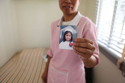 En el dormitorio que tiene reservado en la casa donde trabaja, esta empleada filipina muestra el retrato de su hija, a la que no ve desde hace dos años.
