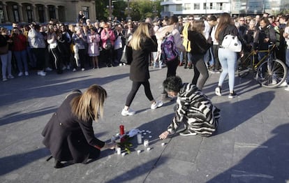 Dos mujeres ponen velas en la concentración de repulsa por la muerte en una pelea de un menor en San Sebastián.