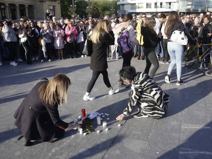 Dos mujeres ponen velas en la concentración de repulsa por la muerte en una pelea de un menor en San Sebastián.