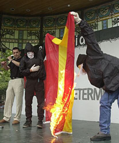 Otegi observa cómo dos encapuchados queman la bandera.