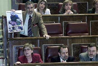 Gaspar Llamazares muestra a José María Aznar en el Congreso un cartel sobre los horrores de la guerra.