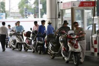 Varios motoristas hacen cola para llenar el depósito de sus ciclomotores en una gasolinera de Shanghai, China. EFE/Archivo