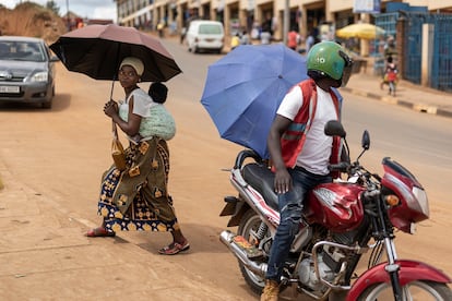 Una mujer con su bebé en la espalda camina por el mercado de Mulindi, en Kigali, en junio de 2023.