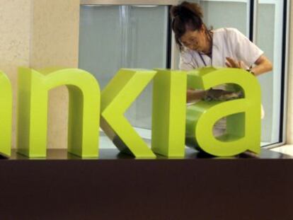 Una operaria limpia el logo de Bankia. EFE/Archivo