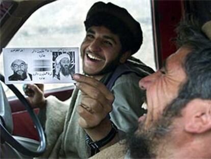 Dos milicianos ríen mientras muestran las fotos de Omar y Bin Laden junto a sus recompensas, a su regreso de Tora Bora sin lograr encontrarlos.
