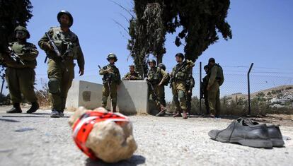 Soldados israelíes junto a un par de zapatos, supuestamente del atacante palestino que el lunes hirió a dos militares al norte de Hebrón.