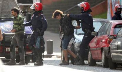 Dos agentes de la Ertzaintza conducen a dos de las 23 personas que ocupaban el 'gaztetxe' (local juvenil) Kukutza, ubicado en el barrio bilbaíno de Rekalde.