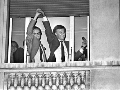 Alfonso Guerra levanta la mano de Felipe Gonz&aacute;lez, asomados a una ventana del hotel Palace, tras conocerse la victoria socialista en 1982.