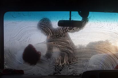 Un joven limpia el cristal del parabrisas de un coche en Daca (Bangladés).