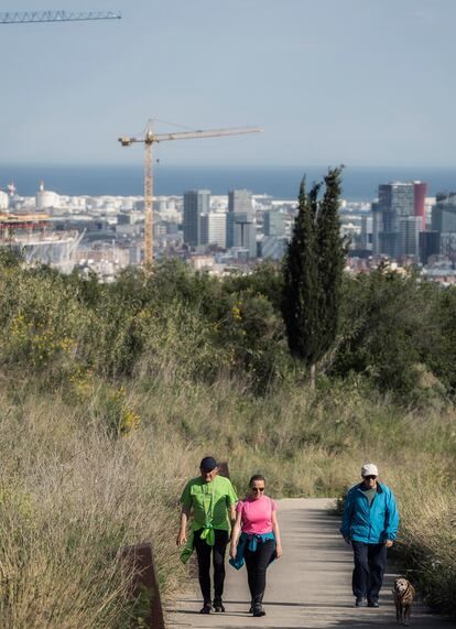 Varias personas pasean por un camino en Finestrelles que une con Collserola, con Barcelona al fondo.