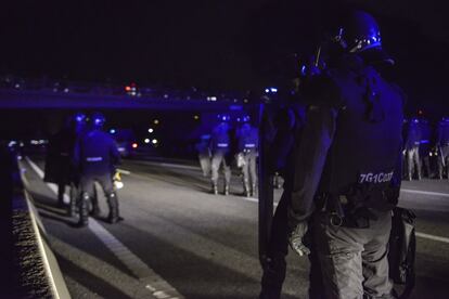 Miembros de la policía montan guardia mientras centenares de personas participan en el nuevo corte de la autopista AP-7, a la altura de Girona