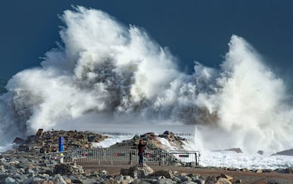 Una persona observa las grandes olas en la playa de la Barceloneta, en Barcelona.