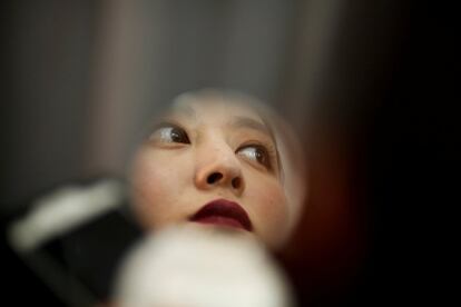 Una modelo se retoca en un pequeño espejo en el backstage durante la Fashion Week de China, en la ciudad de Pekín (China).