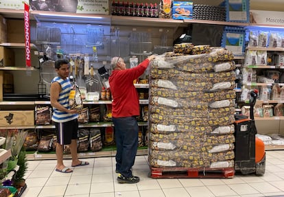Un reponedor carga bolsas de carbón en una de las estanterías del supermercado Alcampo de Vallecas.