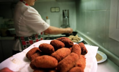 Una mujer cocina croquetas.