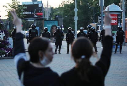 Dos activistas opositoras hacen el símbolo de la victoria frente a una barrera policial durante las protestas masivas del lunes.