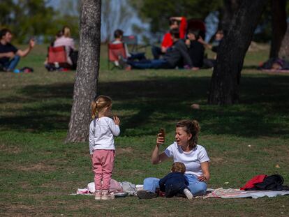 Una mujer con dos niños toma fotos alejada de otros grupos en la Casa de Campo en Madrid.