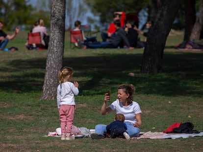 Una mujer con dos niños toma fotos alejada de otros grupos en la Casa de Campo en Madrid.