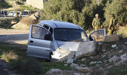 Dos militares israelíes cerca del coche tiroteado en Hebrón este viernes.