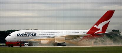 Bomberos del aeropuerto de Singapur arrojan espuma sobre el motor del avión A-380 de la línea aérea Qantas, nada más aterrizar.