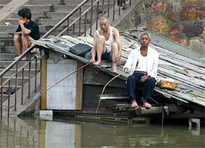 Dos hombres pescan desde el techo de un edificio inundado en Yueyang, junto al lago Dongting.