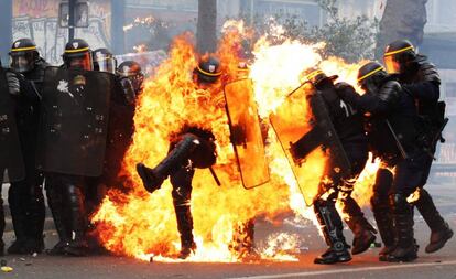 Miembros de la policía antidisturbios intentan escapar de las llamas durante la marcha de trabajadores del 1 de mayo, en París.