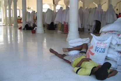 Un niño duerme junto a unos sacos de arroz en una mezquita de un campo de refugiados de Banda Aceh.