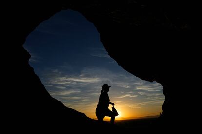A hiker walks past the Hole-in-the-Rock at Papago Park during sunrise July 17, 2023, in Phoenix