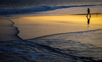 Un hombre camina al amanecer por la playa de Ondarreta de San Sebastián.