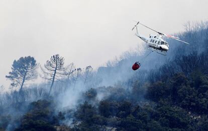 Un helicóptero realiza una maniobra para arrojar agua sobre eln incendio forestal en Barx, el 7 de agosto.