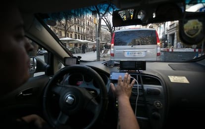 Un taxista consulta al mòbil la matrícula d'una furgoneta per veure si té llicència.