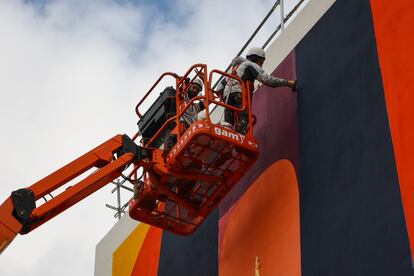 Pablo Ferreiro y Javier Ballesteros pintan el mural de la residencia sobre una grúa.
