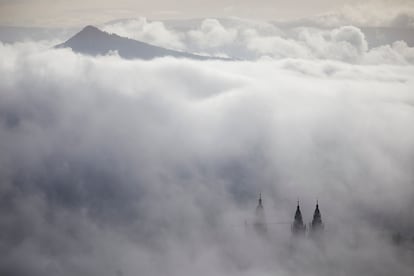 Vista de las torres de la catedral de Santiago entre la niebla, con el monte Pico Sacro al fondo.