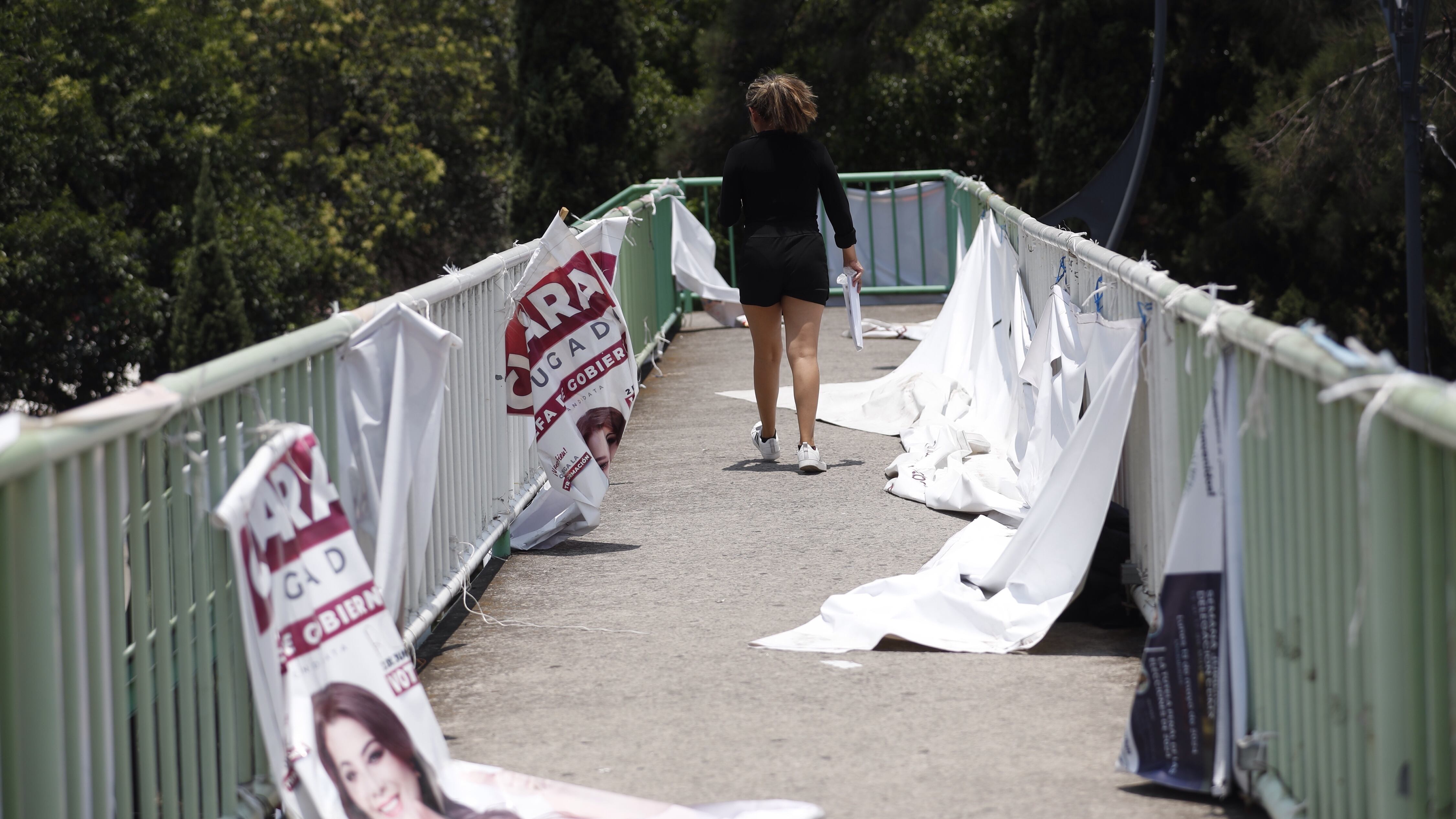  Un mujer camina junto a carteles de propaganda electoral, en Ciudad de México.