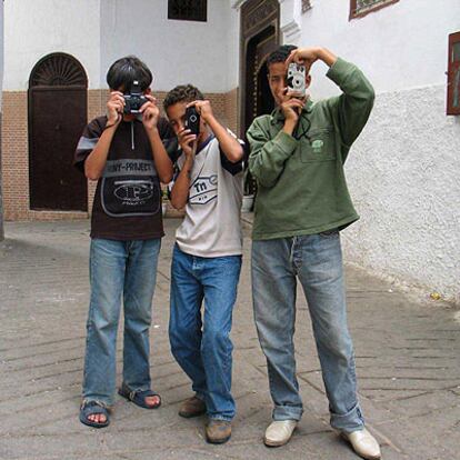 Tres niños marroquíes ensayan con sus cámaras en una calle de Tetuán.