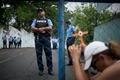 Una mujer que tiene un pariente encerrado por manifestarse, se hinca frente a un oficial afuera de la cárcel de El Chipote, en mayo de 2018.