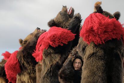 Una niña con un traje de piel de oso baila junto con los adultos durante la reunión ritual anual del oso en Comanesti (Rumania). 