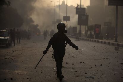 Un polic&iacute;a antidisturbios egipcio cruza la calle durante los enfrentamientos con los partidarios de Morsi.  