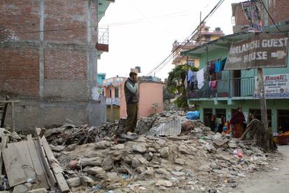 Un hombre habla por teléfono sobre los escombros de un edificio en Melamchi. Sólo en dos de los 17 distritos afectados, las autoridades han empezado a recoger la documentación necesaria para la reconstrucción de las viviendas particulares.