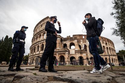 Dos agentes de policía verifican el uso de la mascarilla por parte de transeúntes frente al Coliseo de Roma.