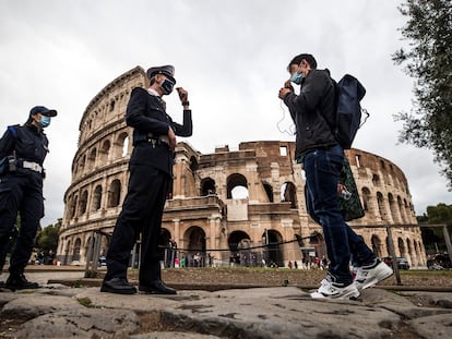 Dos agentes de policía verifican el uso de la mascarilla por parte de transeúntes frente al Coliseo de Roma.