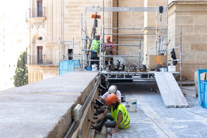 Several workers work on the roof of the Malaga Cathedral.