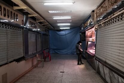 Una mujer saca dinero de su bolso en la galería de la plaza de Quintana, donde solo queda abierta la carnicería Villegas, que también cerrará este sábado ante la construcción del LIDL en el espacio.