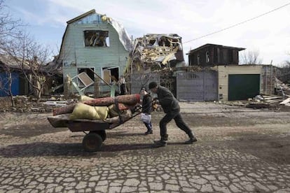 Un hombre empuja una carretilla ante una casa dañada por los combates en la ciudad de Debáltsevo, este miércoles.